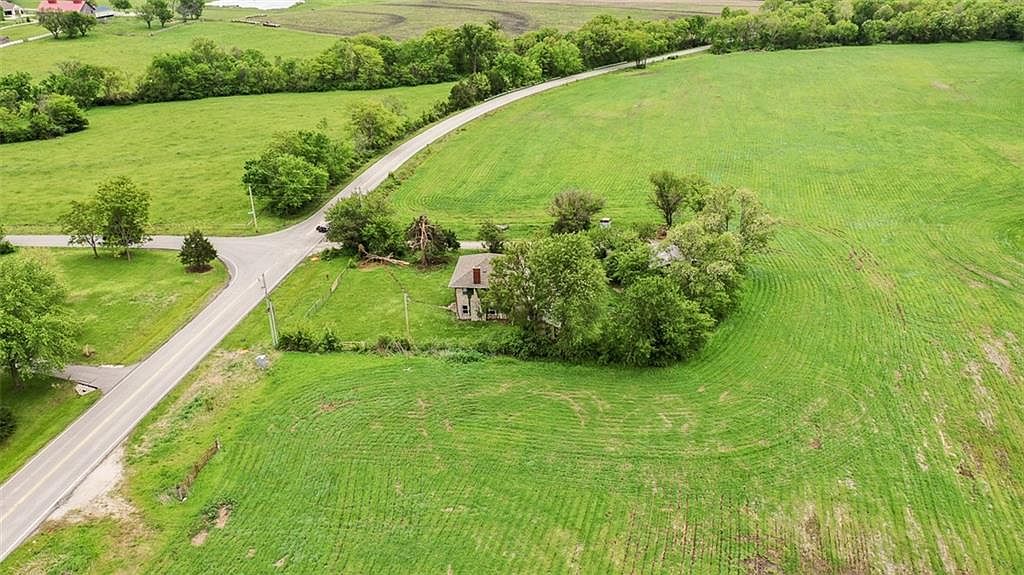 The century-old farmhouse near the eastern frontage, set against a quiet bend in Raytown Road